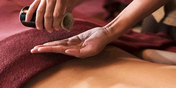 Pessoa com as costas desnudas prestes a receber massagem sensual e erótica com óleo. 