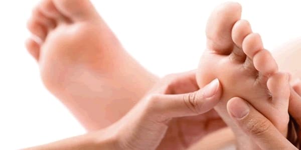 Pessoa recebendo massagem nos pés, do tipo reflexologia.